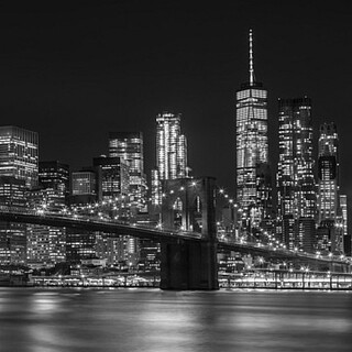 Klassische Nachtaufnahme von Manhattans Skyline und der eindrucksvollen Brooklyn Bridge. Die Lichter der Metropole spiegeln sich im East River. Eine herrliche monochrome Stadtansicht aus dem Brooklyn Bridge Park in exzellenter BildqualitÃ¤t!  - Melanie Viola